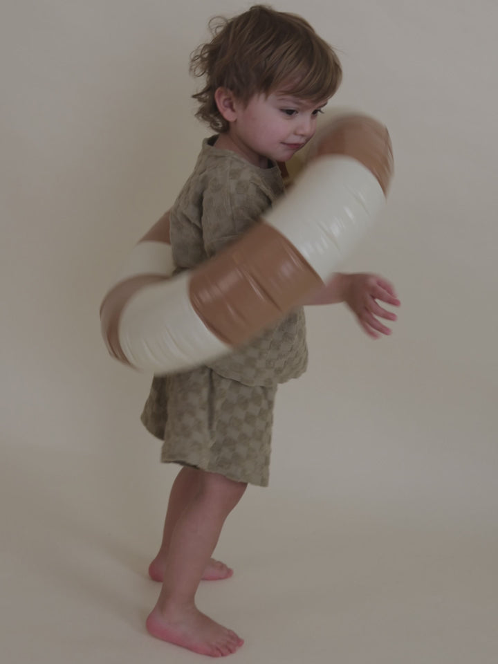toddler in beige checkerboard terry cotton boxy t-shirt & matching shorts playing with pool ring 