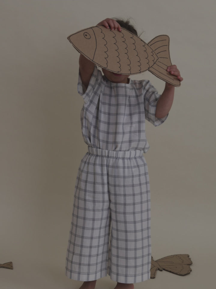 toddler in wide leg pants with navy window check & matching boxy t-shirt holding cardboard fish