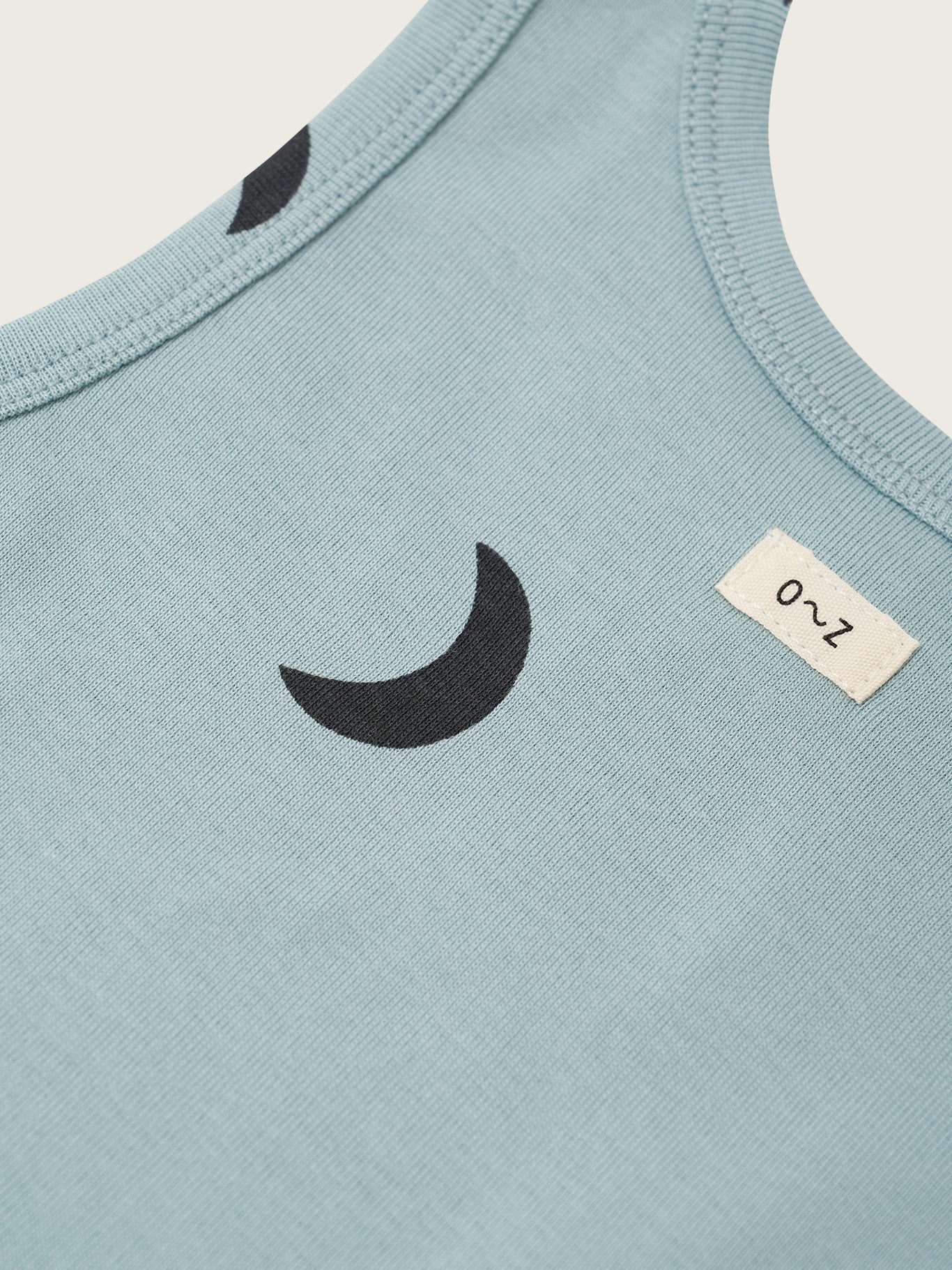 Light blue sleeveless shirt with black crescent moon design and size label on a white background