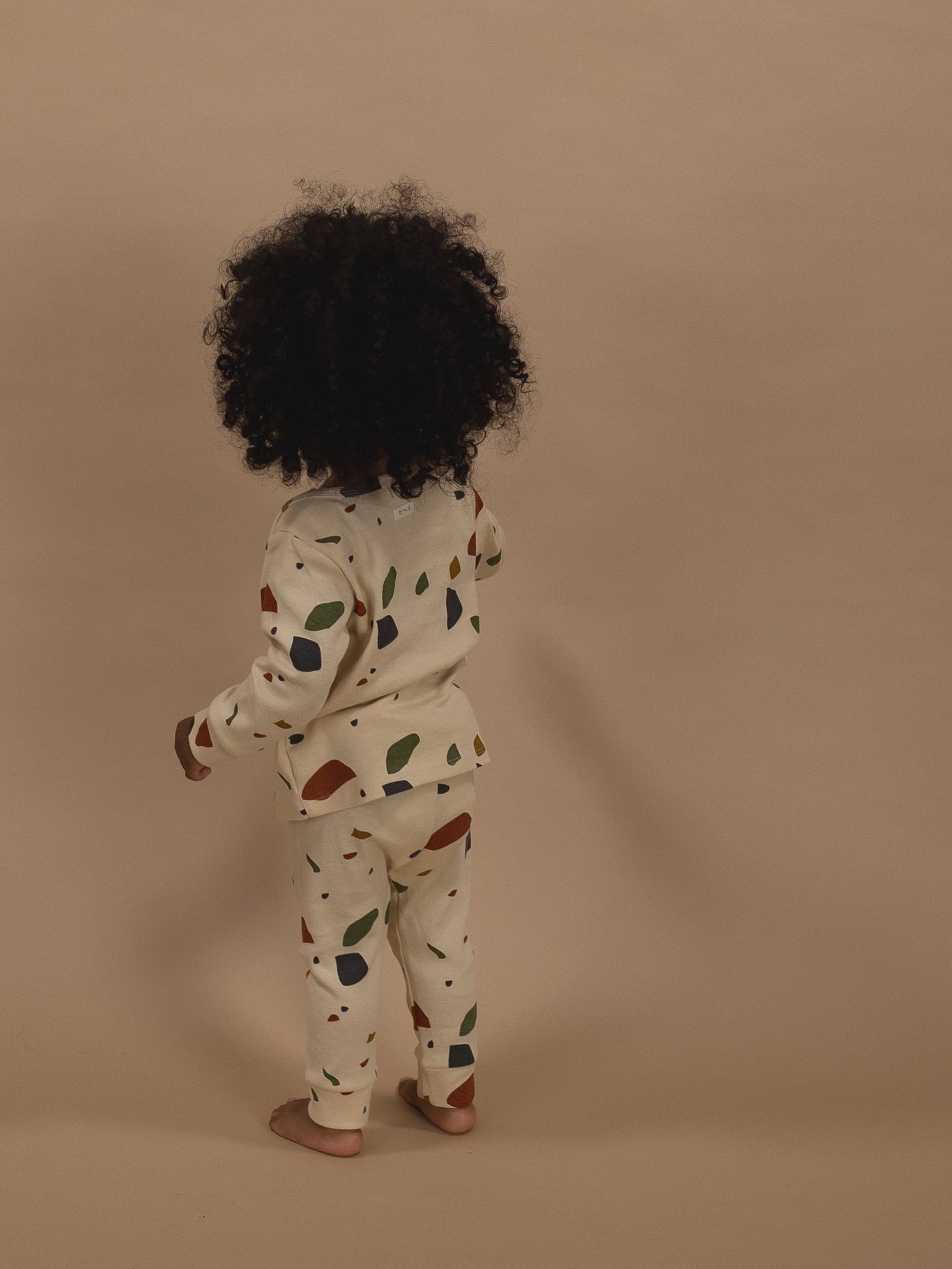 back of toddler in cream ribbed cotton long-sleeved top & leggings set with terrazzo print
