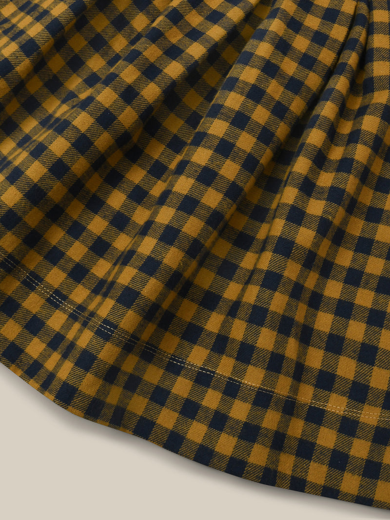 close up of checkered navy and yellow gingham apron-style flannel skirt with adjustable straps