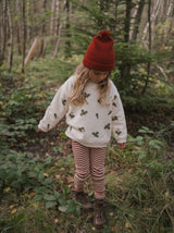 toddler in christmas holly & candy cane sweatshirt red stripes leggings beanie & boots in forest