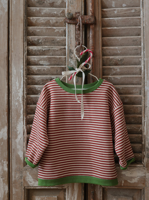 toddler christmas red stripes sweatshirt with green trims hanging on rustic door with candy cane & bow 