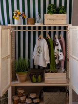 toddler sweatpants & sweatshirts hanging in rattan wardrobe decorated with flowers plants & baskets