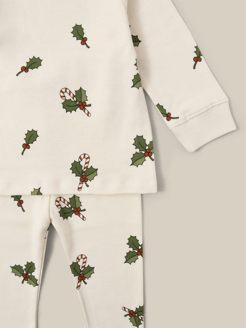 close up of cream organic jersey pyjamas set with holly & candy cane prints