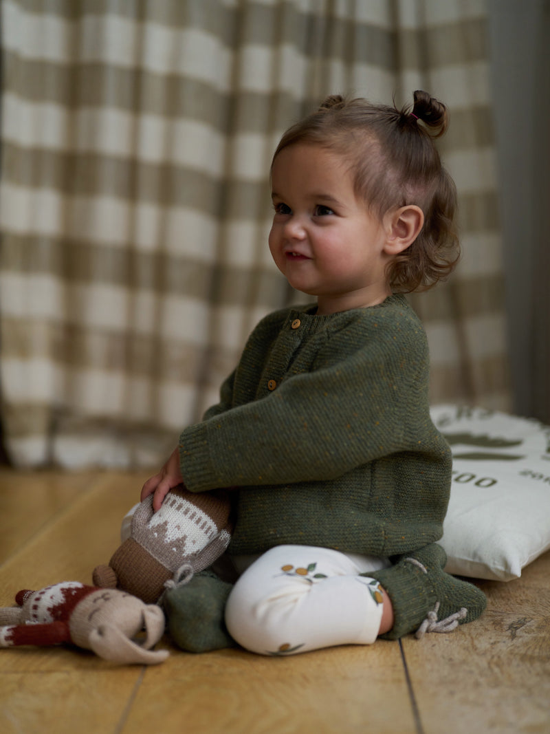 toddler in forest moss green wool cardigan cream leggings & wool booties playing with wool toys