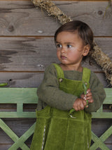 toddler wearing boxy wool green jumper & pea pod green cotton cord overalls with pea pods in hands