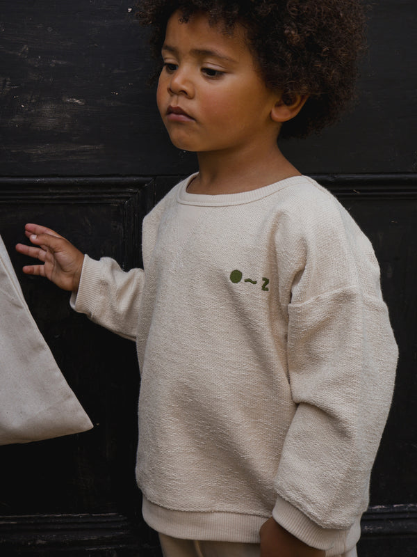 toddler in cream undyed cotton sweatshirt with O ~ Z embroidered in green