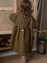 toddler wearing navy & yellow gingham dress with buttons on the back & gathered waist opening rattan wardrobe