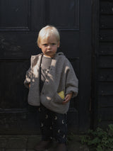 toddler in oatmeal cream wool jacket with pear in pocket & matching black sweat set with moons