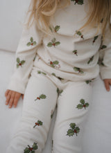 close up of toddler in organic natural jersey in cream with holly & candy cane sitting on sofa