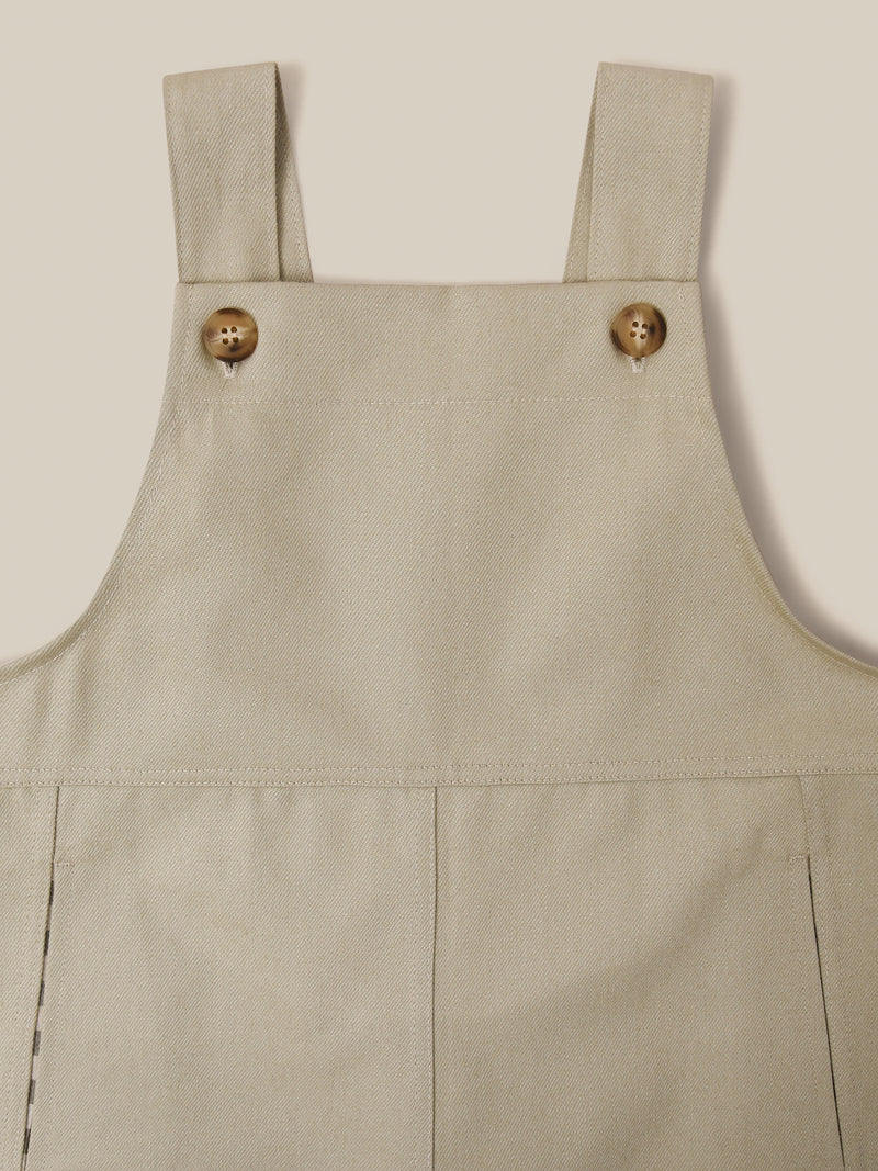 close up of twill cotton oversized farmers dungarees in grey with buttons & side in-seam pockets with gingham finish 