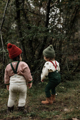 toddlers in christmas stripes sweatshirt & holly sweatshirt with tights beanies & boots playing in forest