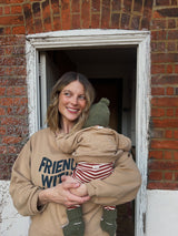 woman in brown slogan sweatshirt carrying baby in matching sweatshirt leggings wool beanie & booties