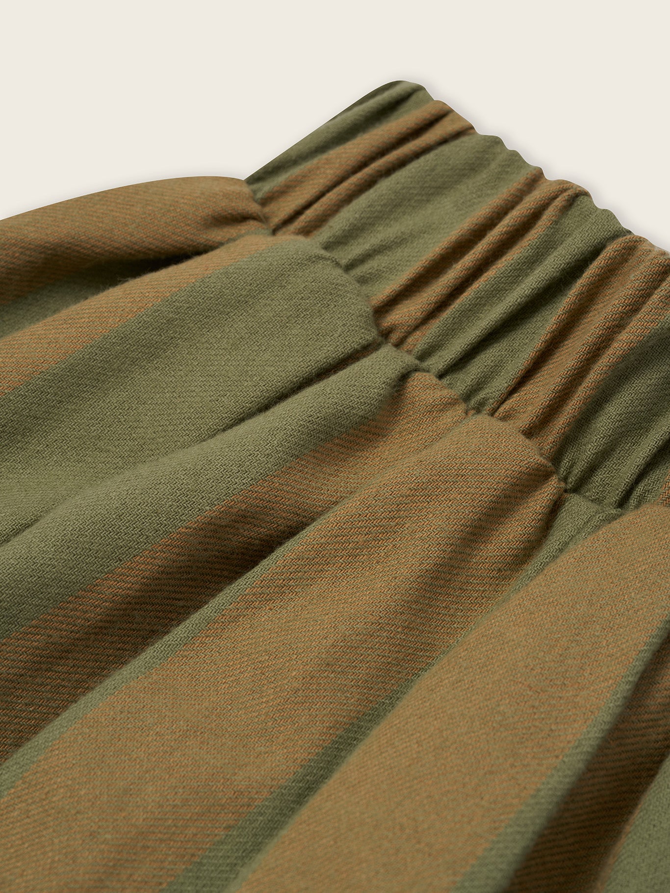 close up of flannel balloon pants in cream and green stripes, with elastic waistband